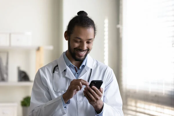 携帯電話を使ってアフリカ系アメリカ人の若い医者を微笑む. — ストック写真