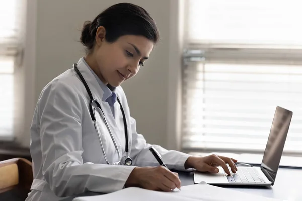 Focused Indian female doctor working in modern office — Stok fotoğraf