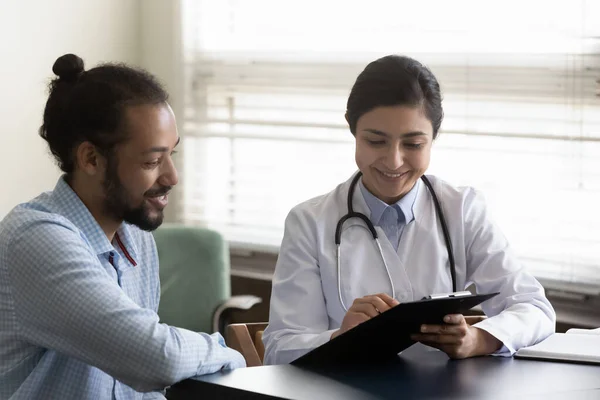 Happy young Indian doctor communicating with patient. — Stockfoto