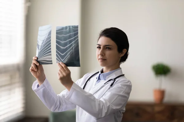 Focused millennial Indian female doctor analyzing x-rays. — Stock Photo, Image