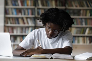 Odaklanmış yeni nesil Z Siyahi üniversite öğrencisi notlar yazıyor