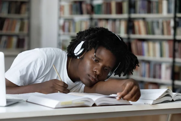 Stanco annoiato pigro nero studente ascoltando audio lezione — Foto Stock