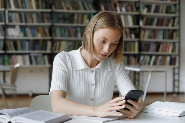 Focused serious female student using online app on mobile phone — Stock Photo, Image