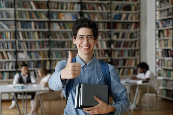 Feliz estudiante adolescente en anteojos y mochila sosteniendo libros —  Fotos de Stock