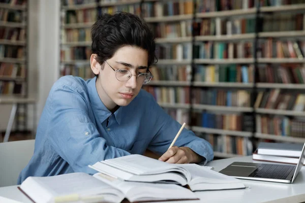 Seriös gymnasieelev som arbetar med examensarbete i biblioteket — Stockfoto