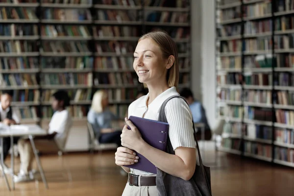 Feliz chica universitaria bastante inteligente caminando en la biblioteca pública de la universidad —  Fotos de Stock