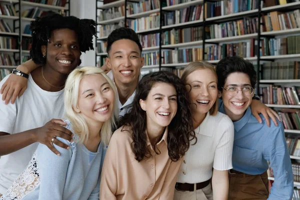 Diverse group of student girls and guys posing in library — Stock Photo, Image