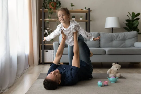 Happy young dad lifting in air small daughter. — Stock Photo, Image