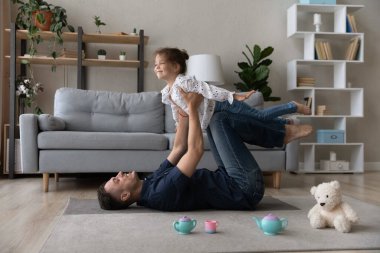 Dertsiz gülen genç baba küçük kızını havaya kaldırıyor..