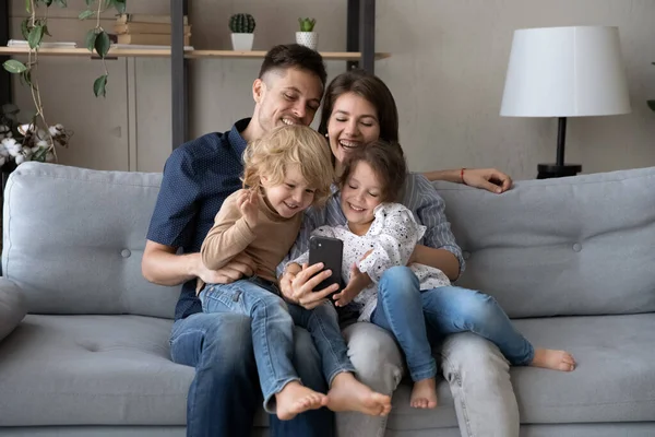 Happy bonding famille de deux générations en utilisant un téléphone portable à la maison. — Photo