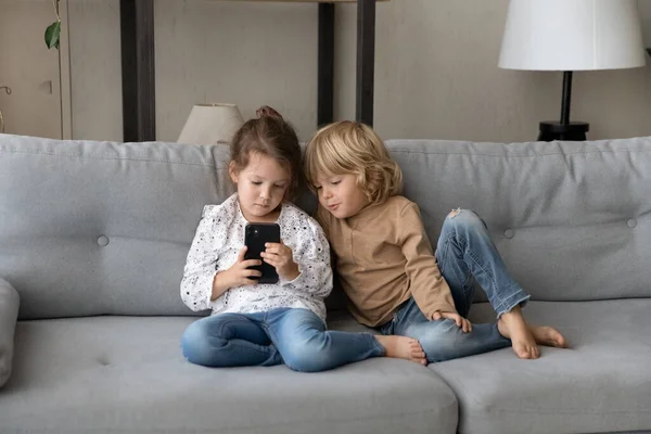 Glada vänliga små barn som leker på smartphone. — Stockfoto