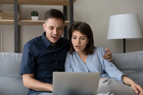 Удивлённая молодая семейная пара смотрит на экран компьютера. — стоковое фото