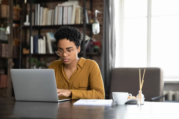 Fokuserad afro amerikansk affärskvinna arbetar på laptop hemma — Stockfoto