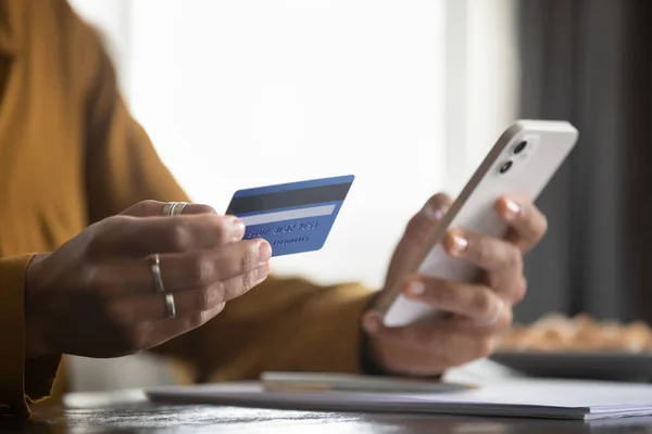 Жінка тримає смартфон, використовуючи кредитну картку, покупки онлайн — стокове фото