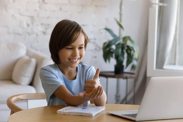 Glimlachende jongen met slechthorendheid die thuis online studeert — Stockfoto