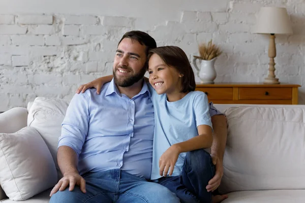 Happy schoolkid son and dad sitting together on couch — Stock Photo, Image