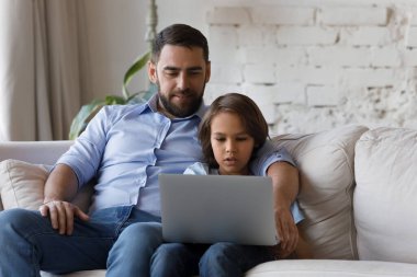 Mutlu baba, okullu çocuğun internet uygulamasını kullanmasını izliyor.