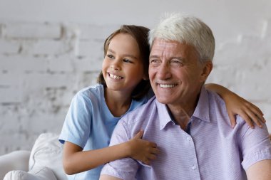 Düşünceli, mutlu torun çocuğu. Hayalperest, gri saçlı büyükbabaya sarılıyor.