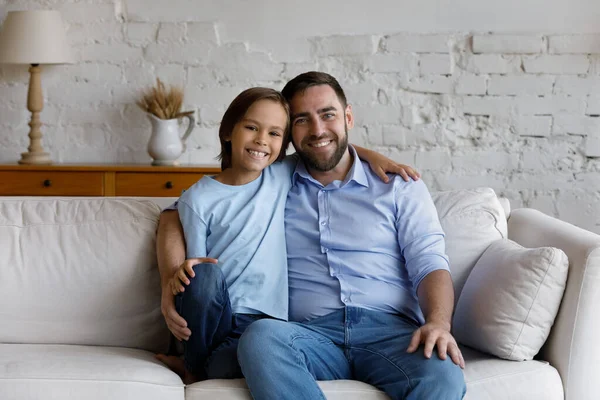 Feliz padre e hijo escolar sentado en el sofá en casa —  Fotos de Stock