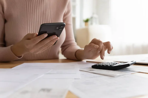 Mujer hace cálculos, pagar facturas a través de la aplicación de banco electrónico en el teléfono inteligente —  Fotos de Stock