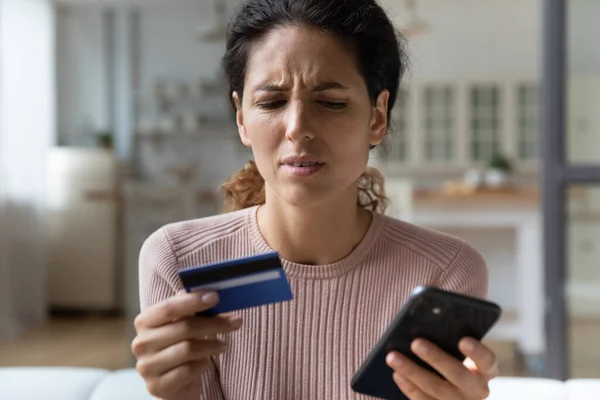 Frown woman holding card and cellphone experiences problems with e-payment — Stock Photo, Image