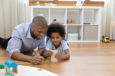 Tatlı çocuk. Babası yerde yatıyor. Akıllı telefonuyla.