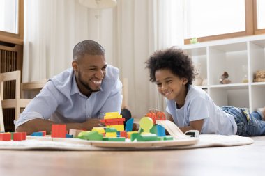 Neşeli Afrikalı baba ve oğul ahşap demiryolu ve tuğla oynuyorlar.