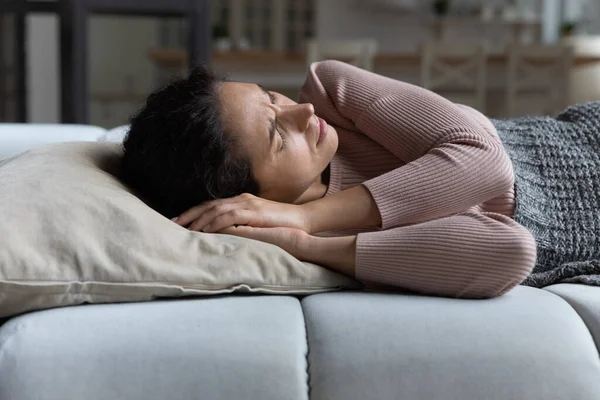 Mulher franzindo a testa deitada no sofá sofrem de sono agitado diurno — Fotografia de Stock