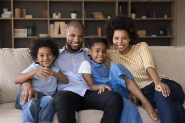 Afrikalı çift ve çocuklar evdeki kanepede oturuyor.