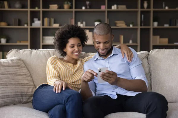 Africana pareja en el amor relajarse en el sofá con teléfono móvil — Foto de Stock