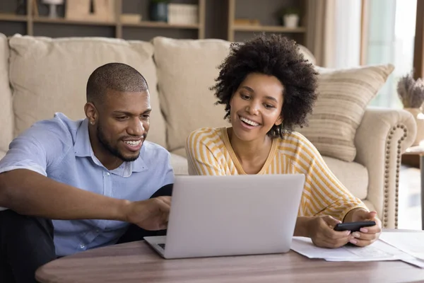 Glimlachend Afrikaans paar berekenen hun inkomsten en uitgaven thuis — Stockfoto