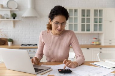 Hispanik kadın hesap makinesi kullanıyor e-banka ile ödeme faturalarını hesaplıyor
