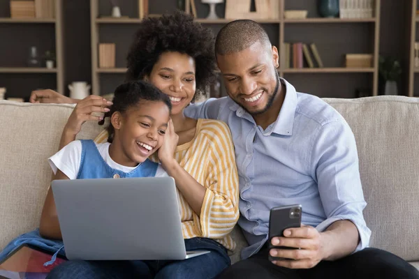 African couple and daughter watch videos on cell phone