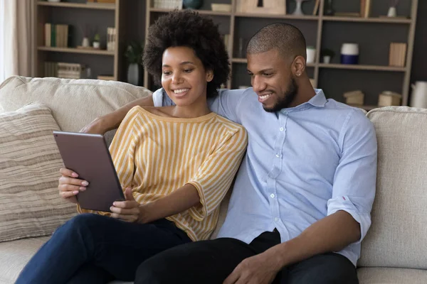 用数码平板电脑在沙发上休息的美丽的非洲夫妇 — 图库照片