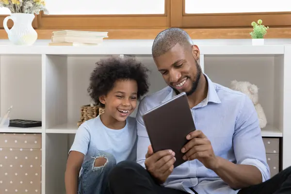 Africano chico y papá disfrutar de la nueva aplicación utilizando el dispositivo de tableta —  Fotos de Stock
