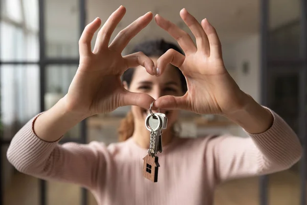 Happy woman hold keys makes heart symbol with joined fingers — Stock fotografie