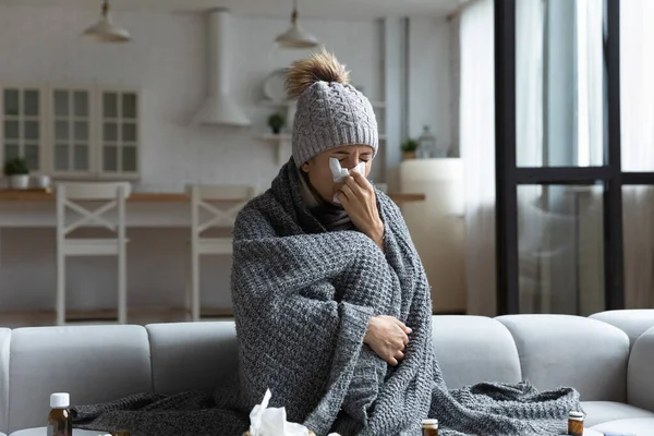 Donna malata coperta di plaid, che soffia naso che cola nel tovagliolo — Foto Stock