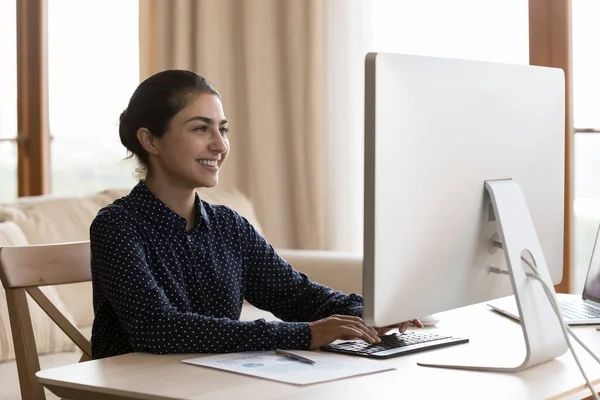 Bilgisayarda çalışan mutlu Hintli genç iş kadını. — Stok fotoğraf