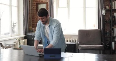 Laptop tableti kullanarak evrak işleriyle uğraşan meşgul bir adam.