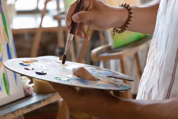 Художник держит палитру в мольберте с маслом, акриловыми красками — стоковое фото