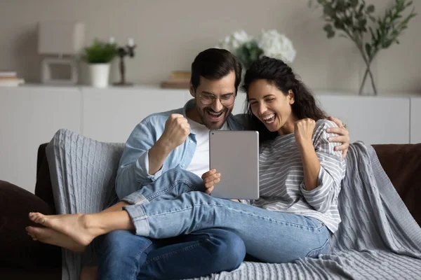 Paar liest Nachrichten auf digitalem Tisch und freut sich über Erfolg — Stockfoto