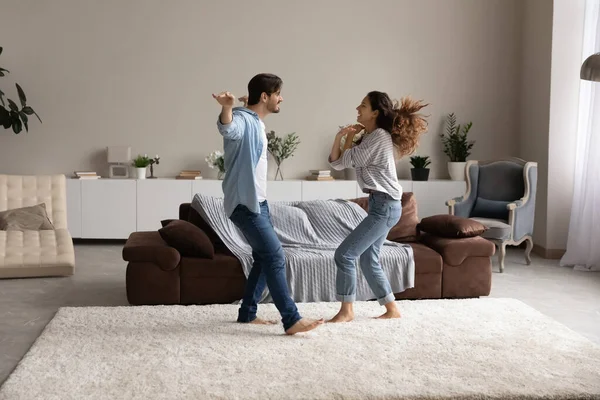 Sorgenfreies aktives Paar tanzt im Wohnzimmer, Blick in voller Länge — Stockfoto