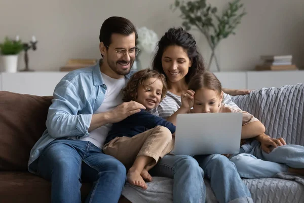 Couple heureux avec des enfants se détendre sur le canapé avec ordinateur portable — Photo