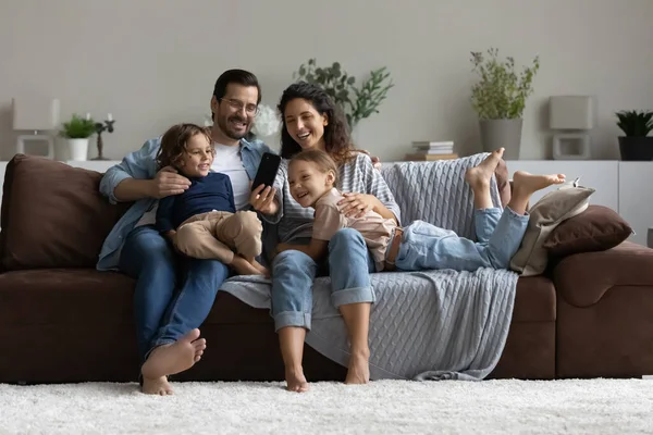 Familia con niños que se divierten usando la aplicación móvil en el teléfono celular —  Fotos de Stock