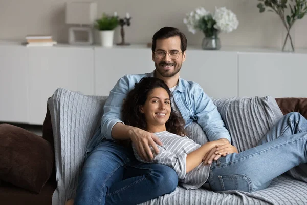 Paar entspannt sich auf Sofa und umarmt posiert mit Blick in die Kamera — Stockfoto