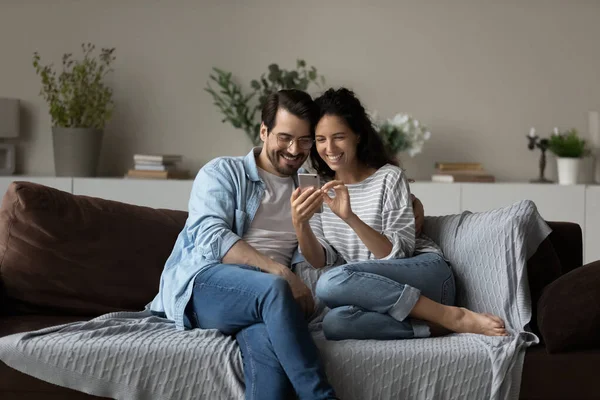 Couple sit on sofa use cell phone watch video online — Stock Photo, Image