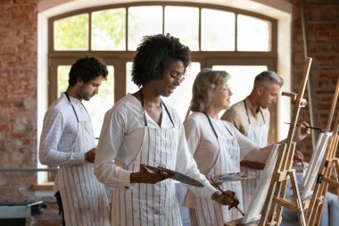 Siyah resim stüdyosu öğrencisi önlüklü kız resim çiziyor.