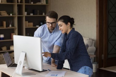 Konsantre olmuş gülümseyen, çok ırklı genç çalışanlar ofiste iş birliği yapıyor..