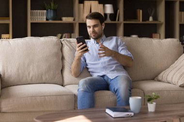 Mutlu, gevşemiş, elinde video kaydı tutan genç adam..