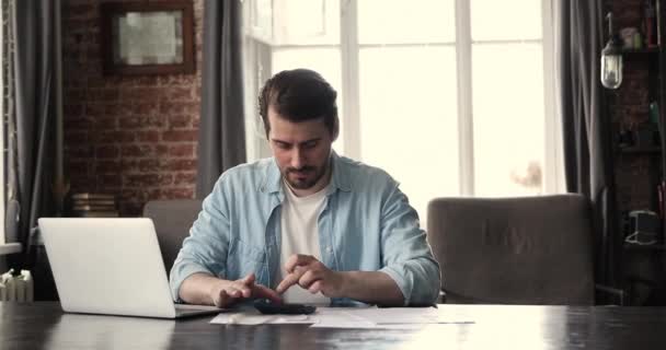 若いビジネスマンのカウント税金は自宅のオフィスでオンラインで請求書を支払う — ストック動画